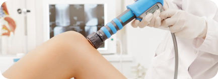 A doctor uses a shockwave therapy gun on a patient's knee